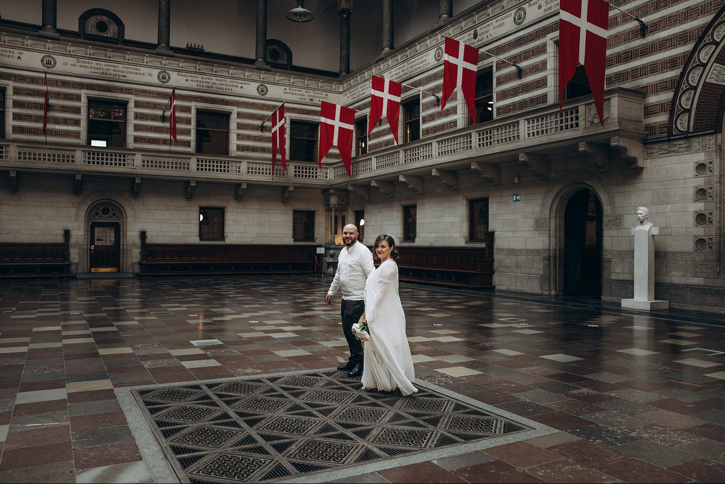 A couple in the flag-lined great hall of Copenhagen City Hall