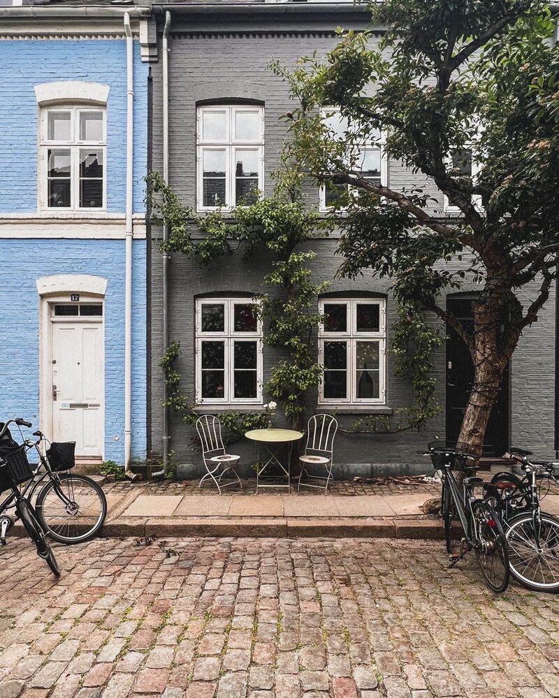 A blue-grey townhouse with a café table and bicycles