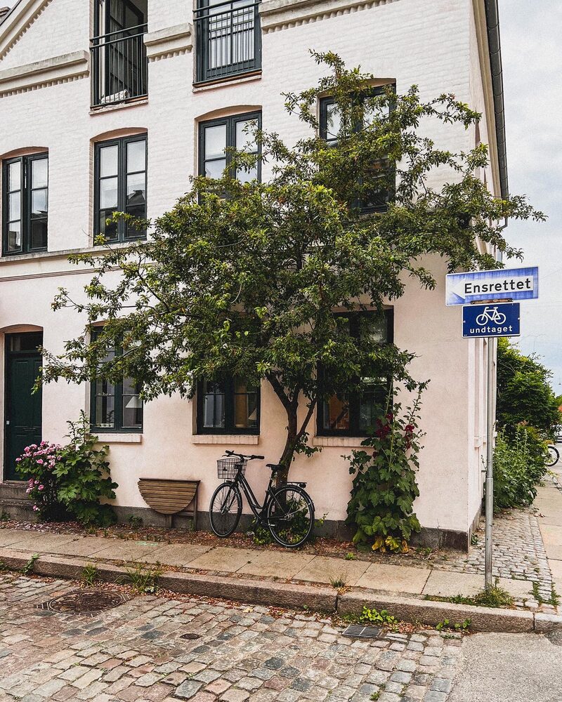 A cream townhouse with greenery and the Krusemyntegade street sign