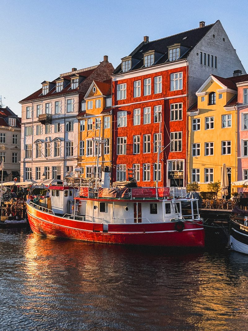 A red boat and colourful houses reflected at golden hour, Nyhavn