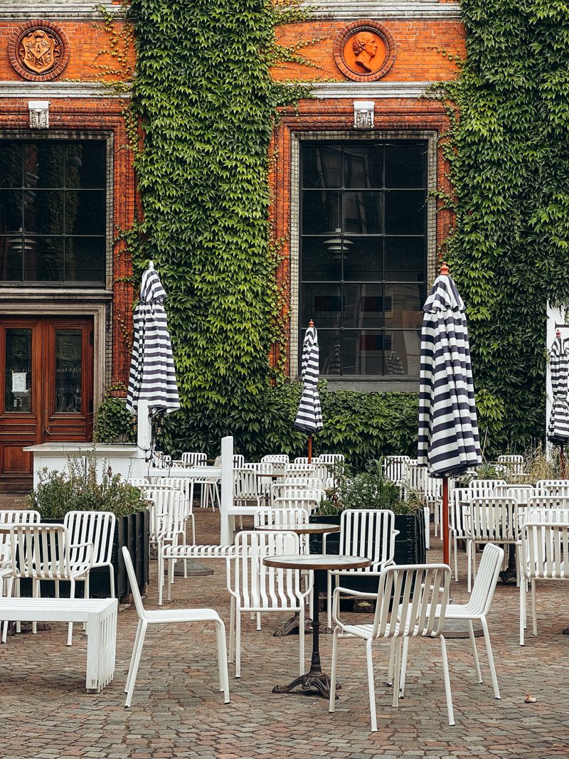 Café tables beneath an ivy-clad Nyhavn façade