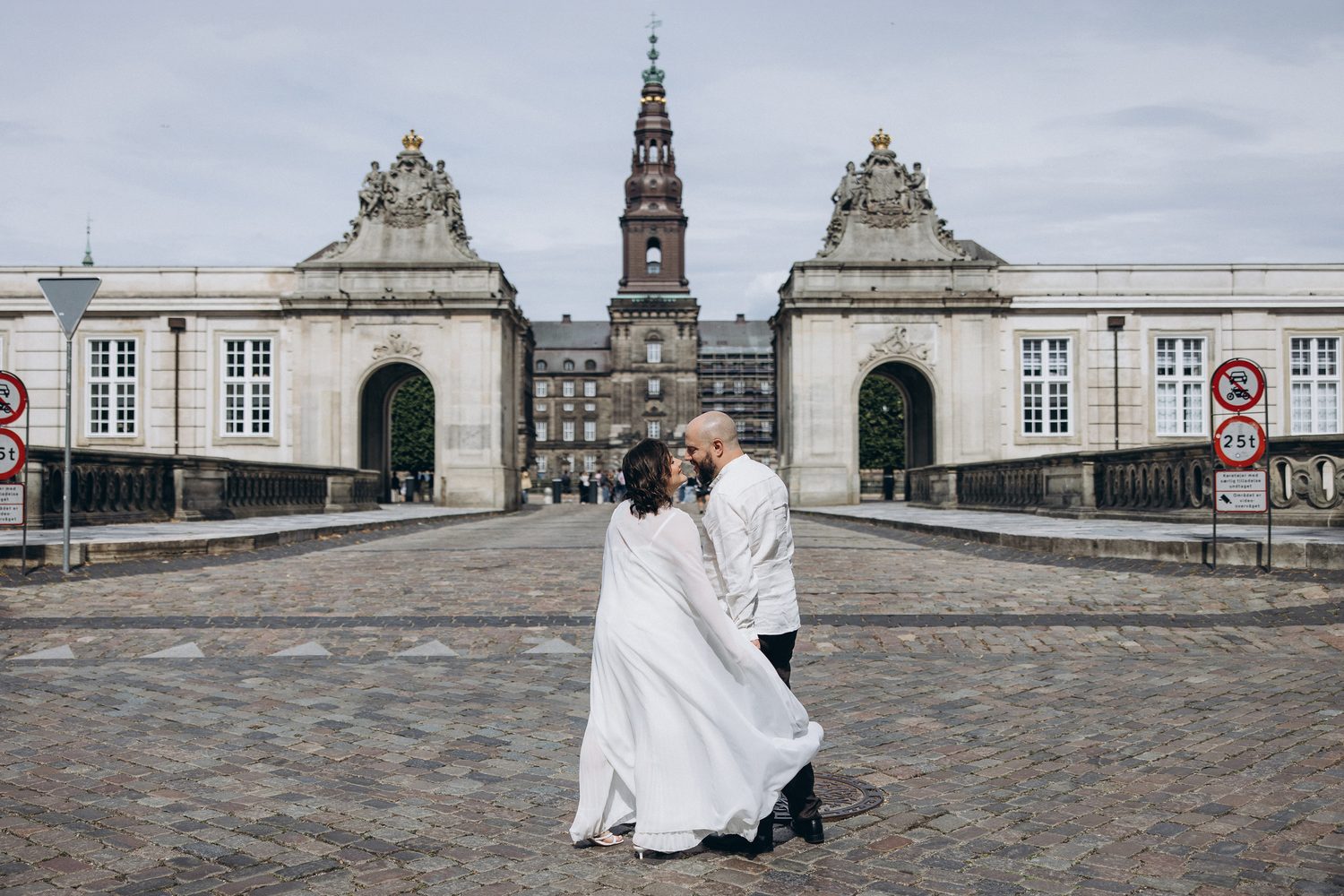 A couple in a dip on the cobblestones before the gates of Christiansborg, Copenhagen