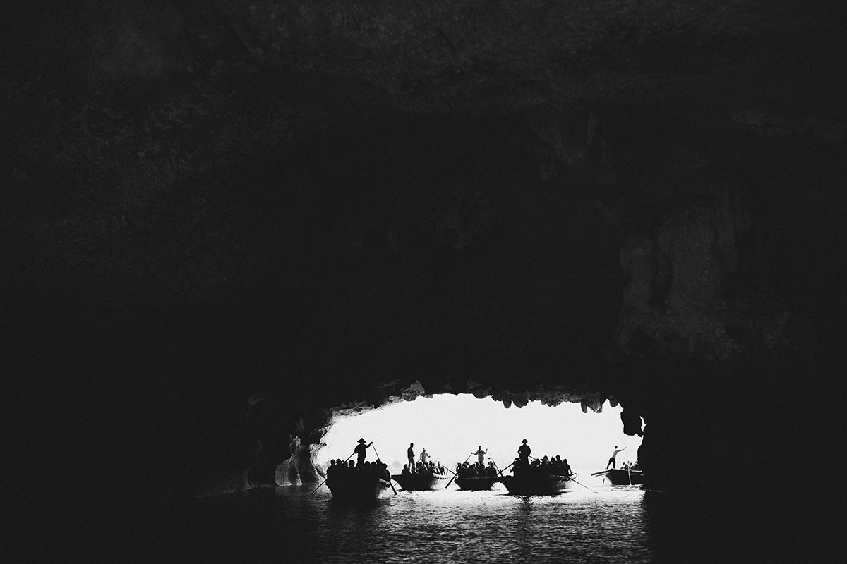 Boats seen through a dark cave mouth, Ha Long Bay, Vietnam
